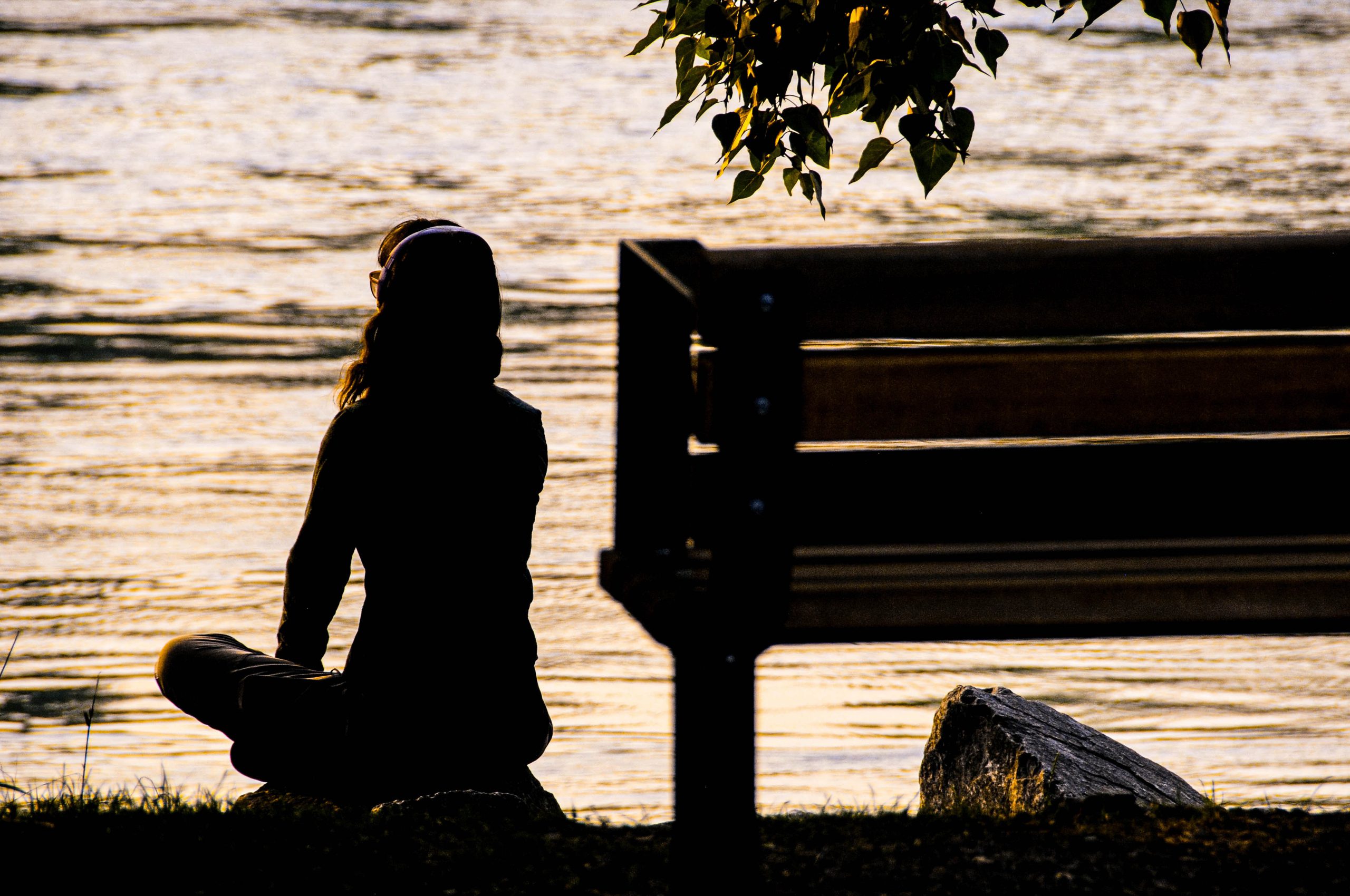 女人的剪影坐在长凳旁，冥想