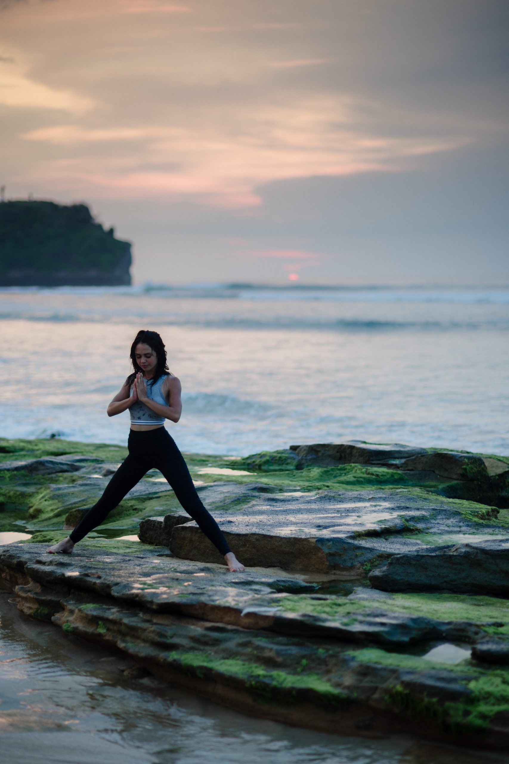 一名女子在岩石海滩上做瑜伽
