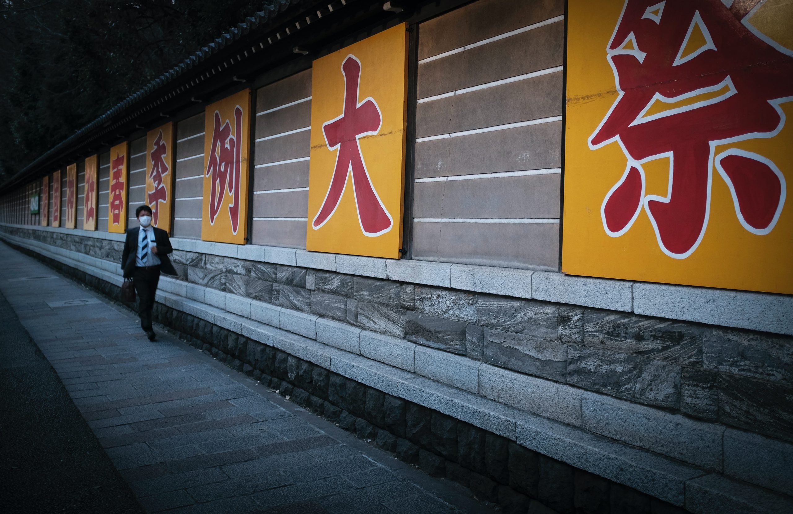 一个男人走在一条挂着黄色日本标志的小路上