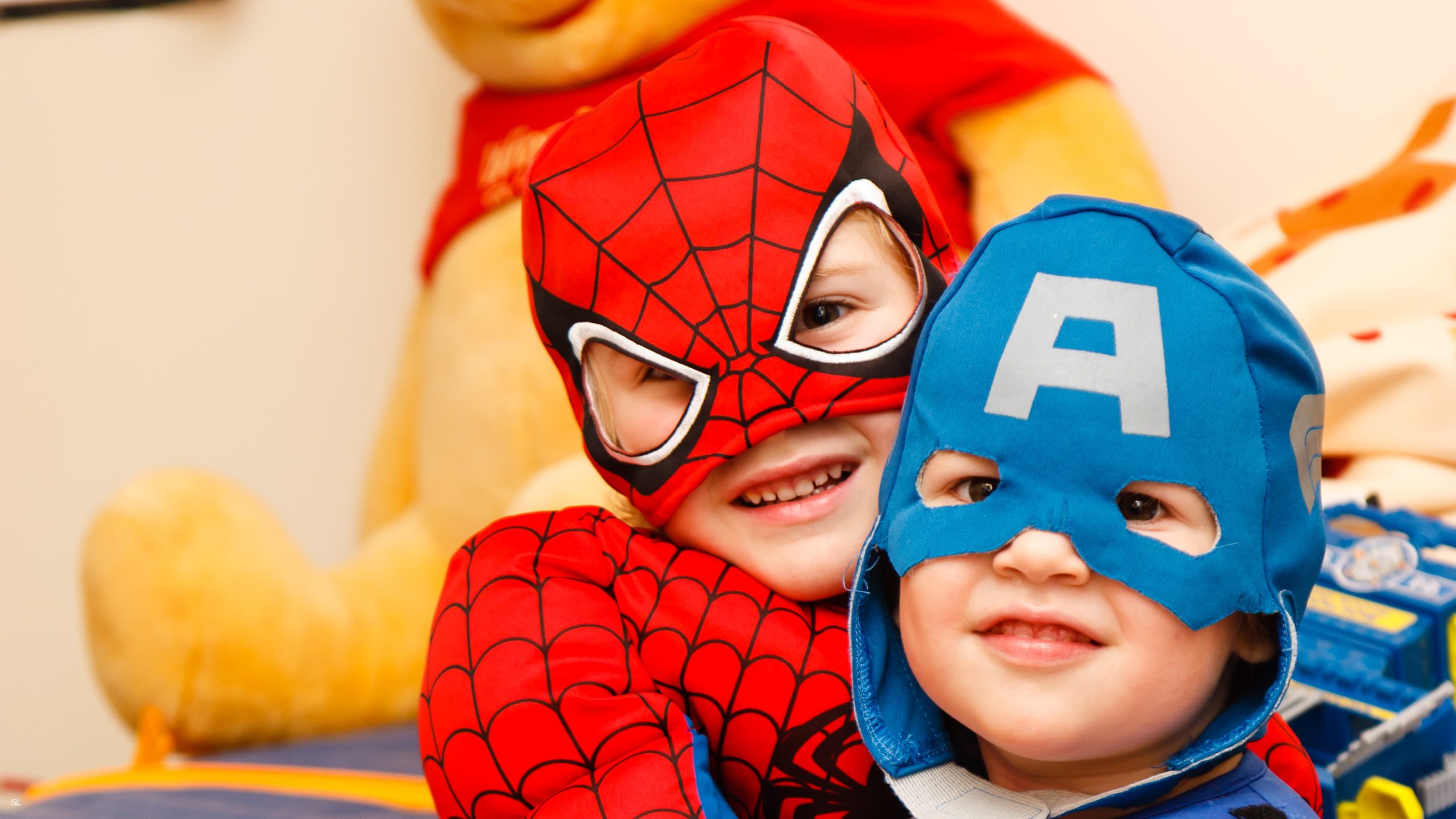 两个男孩抱在一起，打扮成蜘蛛侠和美国队长