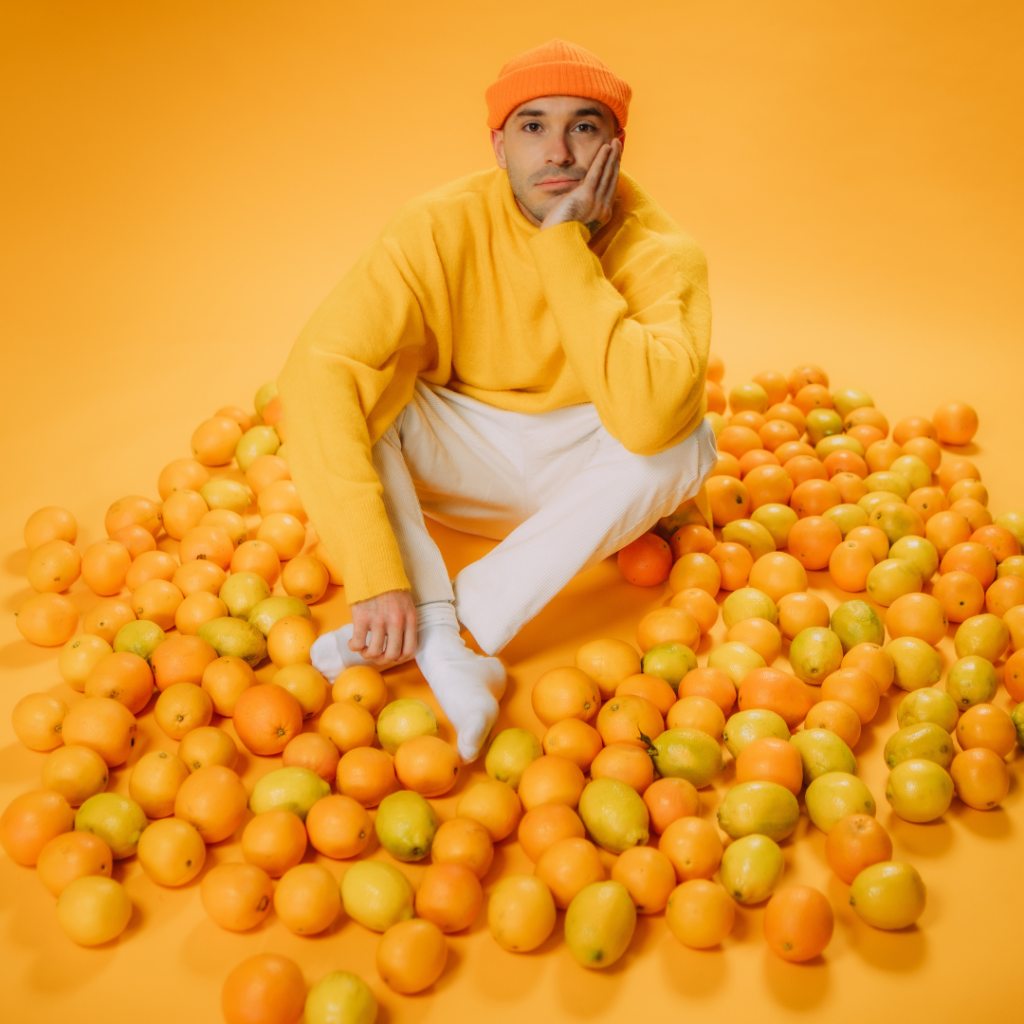 男人坐在橙色的房间里，手里拿着橘子